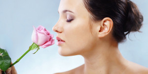 Frau riecht mit geschlossenen Augen an Rose