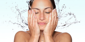 Frau wäscht sich das Gesicht mit Wasser
