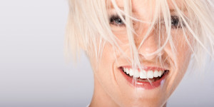 Lachende Frau mit weiß gefärbten, ins Gesicht hängenden, Haaren