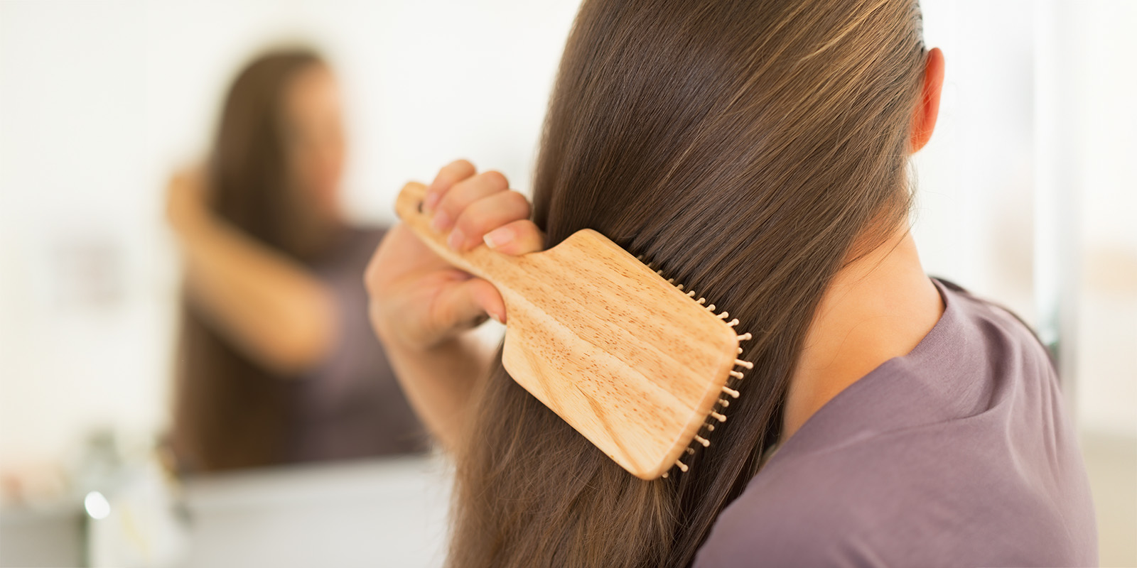 Frau bürstet ihren braunen langen Haare