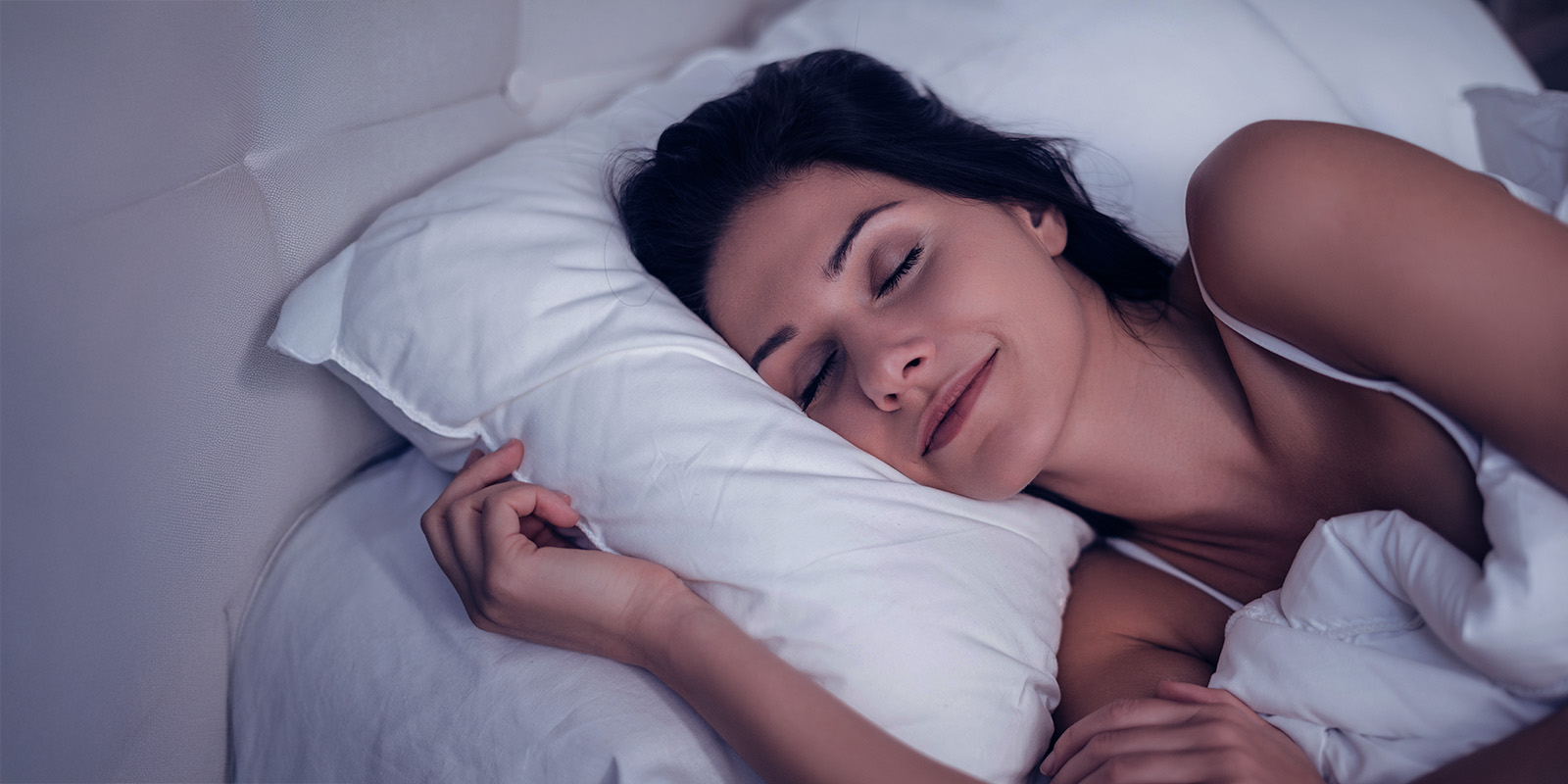 EIne Frau liegt auf der Seite in einem Bett und schläft.