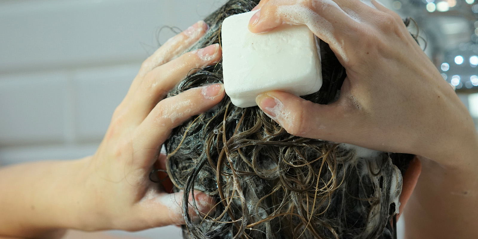 Frau wäscht sich mit festem Shampoo oder Seife die Haare