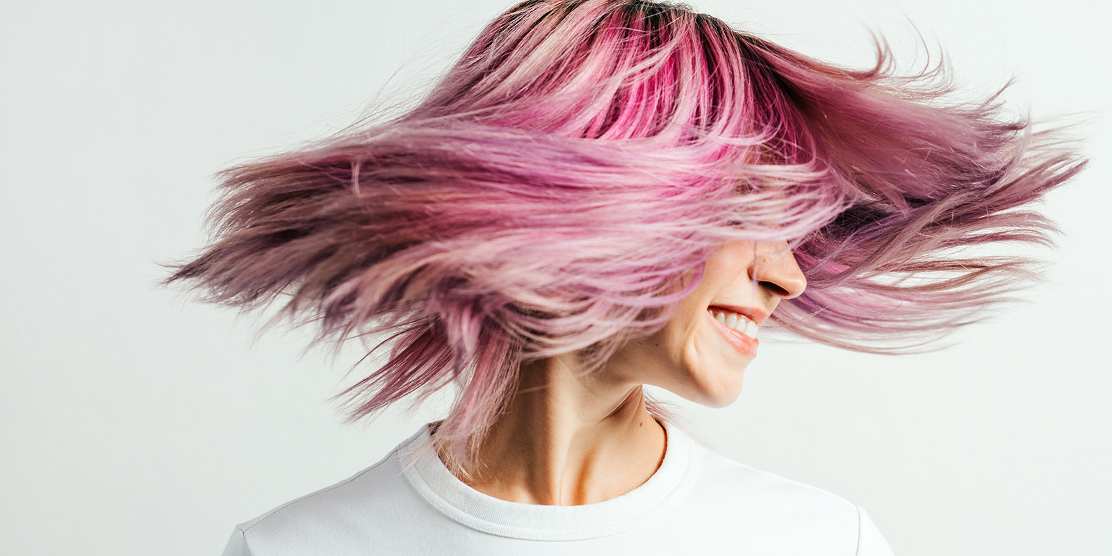 Eine Frau mit halblangem rosa gefärbten Haaren dreht Ihren Kopf so schnell, dass die Haare "schweben".