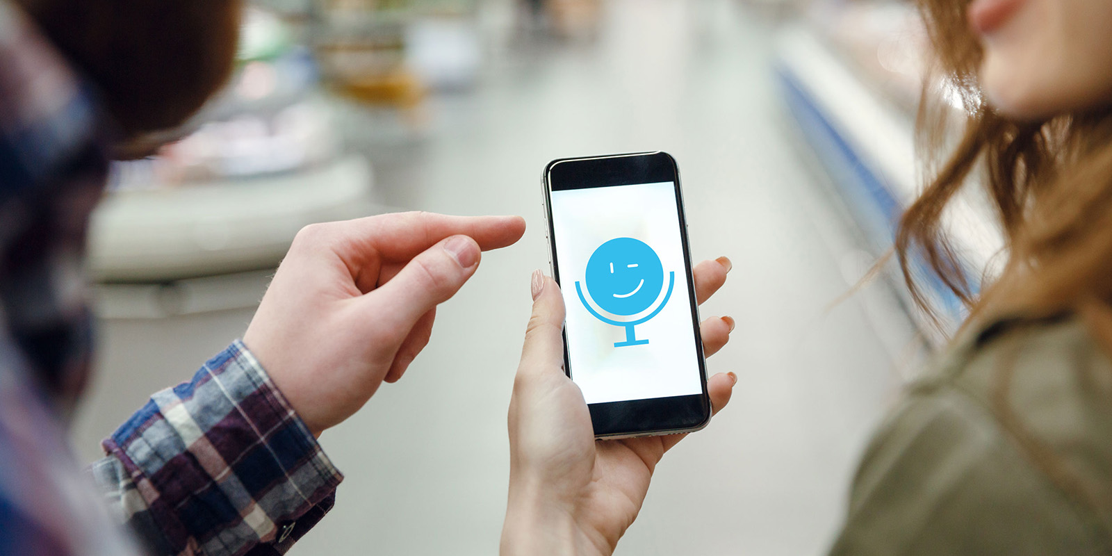 Ein Mann und eine Frau halten gemeinsam ein Smartphone in den Händen mit der Abbildung des Cosmile-Logos.