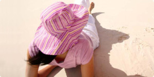 Frau mit Sonnenhut sonnt sich am Strand